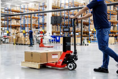 Worker pushing pallet jack in warehouse.